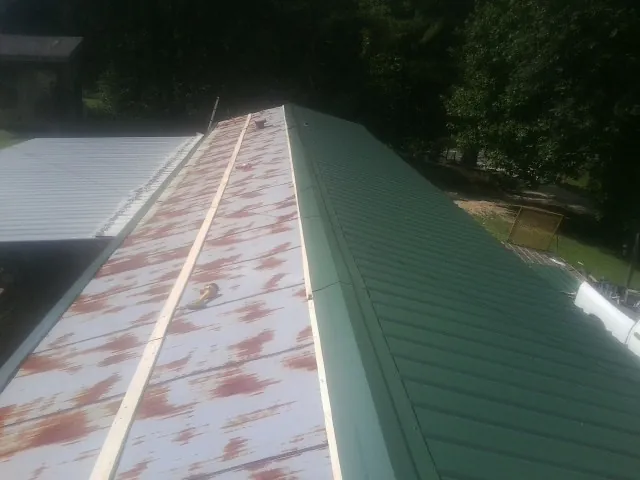 Old rusted panels beside newly installed green metal roofing — Wind Damage Roof Repair by Roofing Brothers in Silver Springs